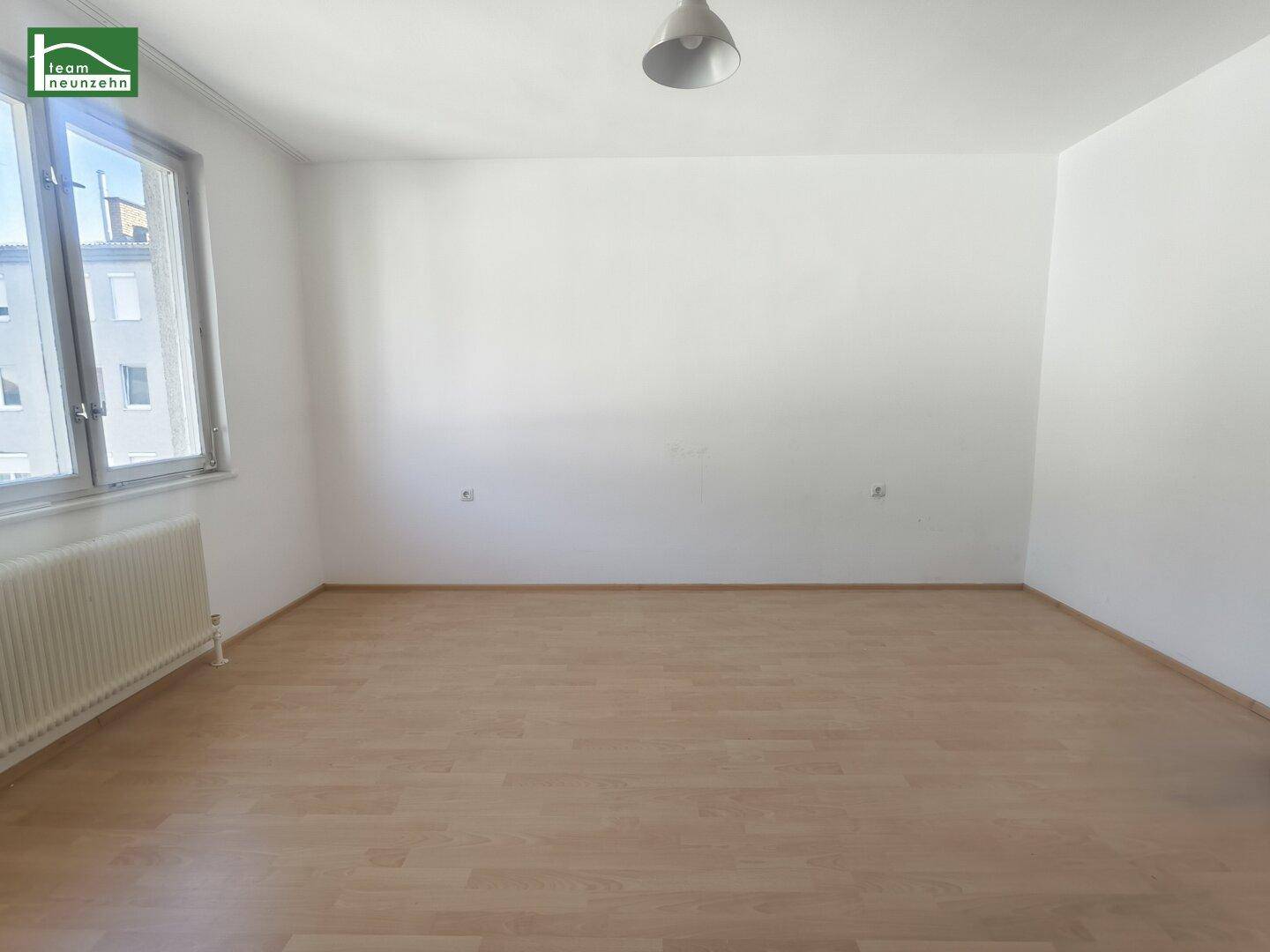 Geräumiges, helles Zimmer mit Laminatboden und großen Fenstern.