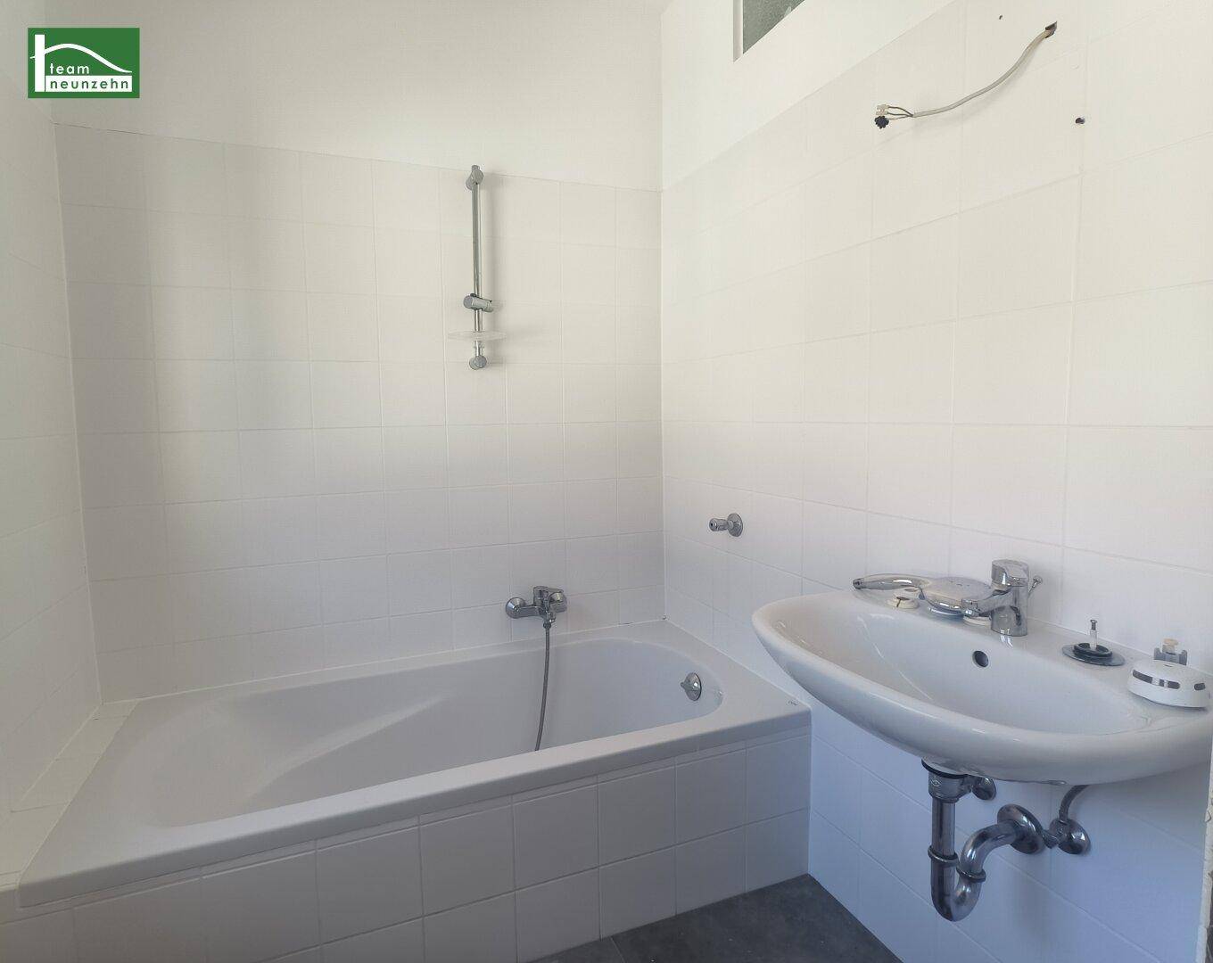 Funktionales Badezimmer mit Badewanne, Waschbecken und weißen Fliesen.