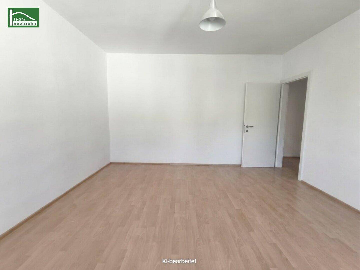 Leeres Zimmer mit Laminatboden und weißer Tür, bereit zur individuellen Gestaltung.