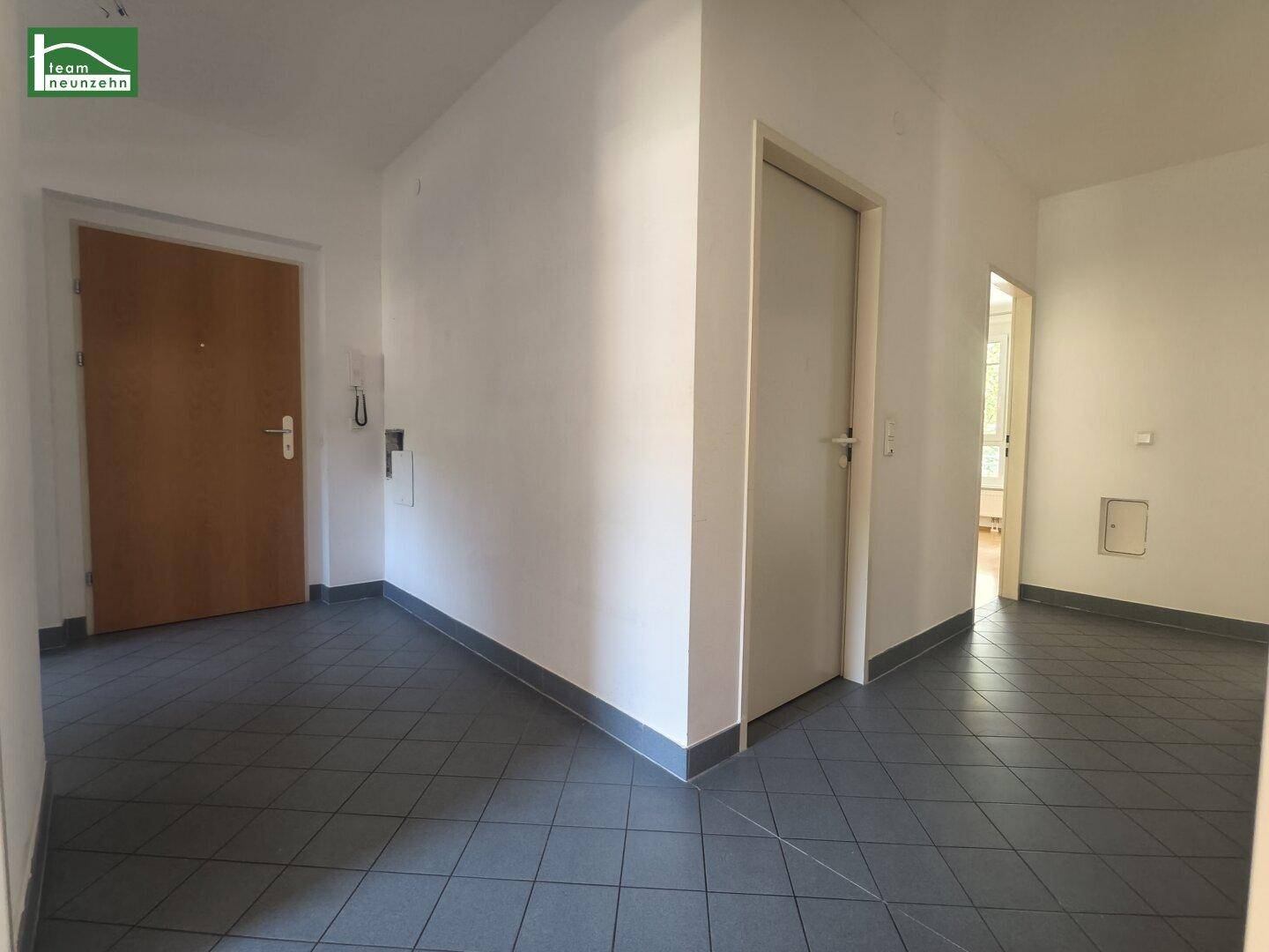 Geräumiger Flur mit Fliesenboden und mehreren Türen, der verschiedene Räume verbindet.