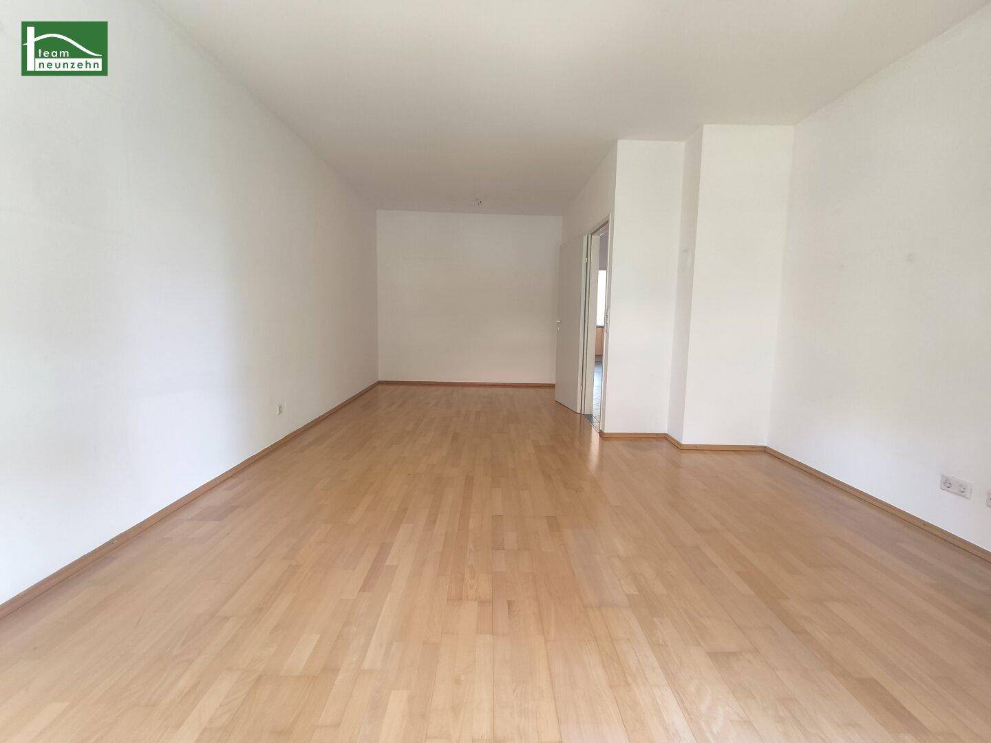 Geräumiges, leeres Zimmer mit hellem Parkettboden und weiß gestrichenen Wänden.