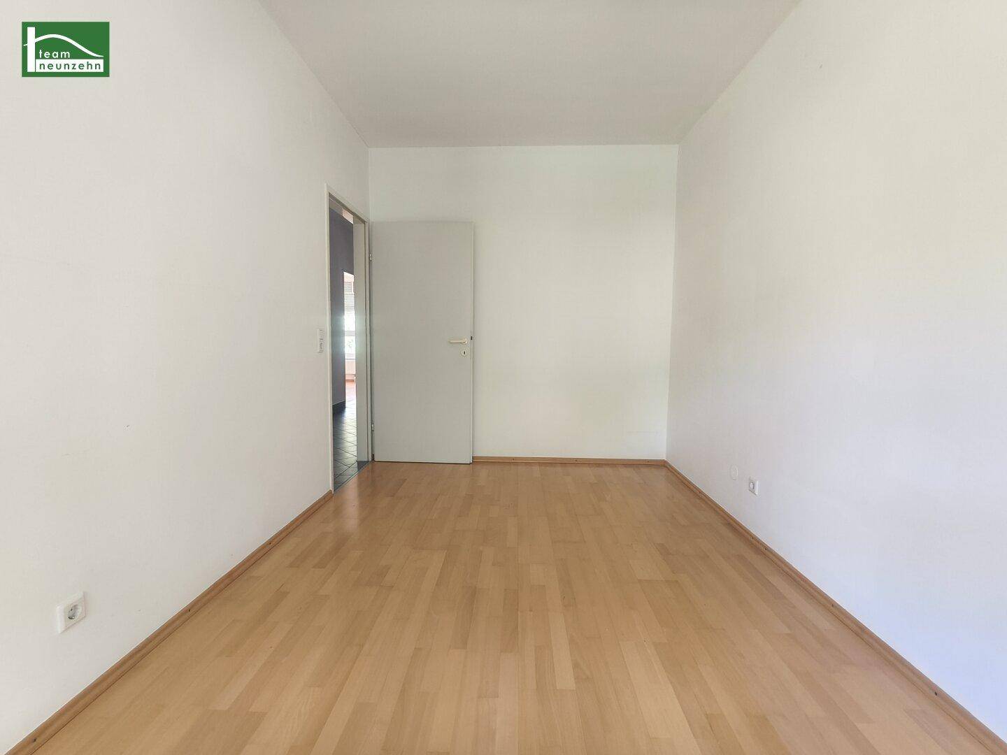 Leeres Zimmer mit hellem Parkettboden und weiß gestrichenen Wänden, bereit zur Einrichtung.