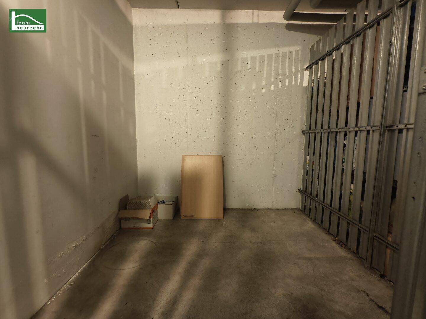 Praktischer Abstellraum im Keller mit Betonboden und Metallabtrennung für zusätzlichen Stauraum.