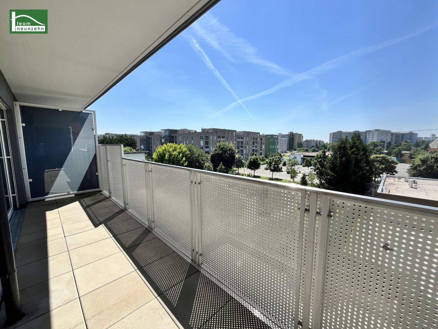 Geräumiger Balkon mit Fliesenboden und Metallgeländer, bietet einen weiten Blick über die Stadt.