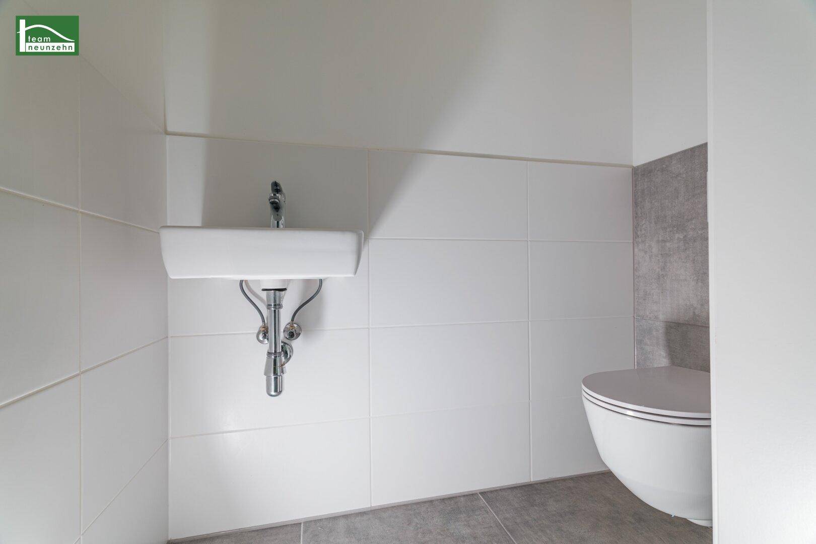 Kleines Gäste-WC mit wandhängendem WC, Waschbecken und weißen Fliesen.