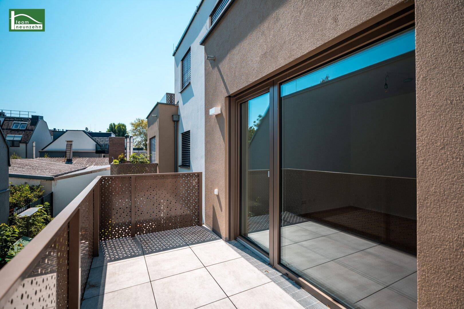 Sonniger Balkon mit Fliesenboden und moderner Lochblech-Brüstung, angrenzend an das Gebäude.