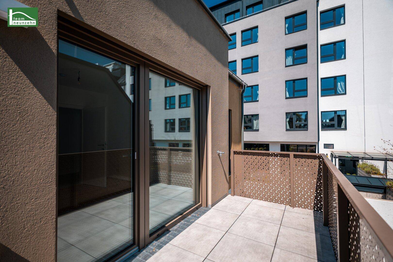 Geräumiger Balkon mit Blick auf die umliegenden Gebäude und viel Tageslicht.