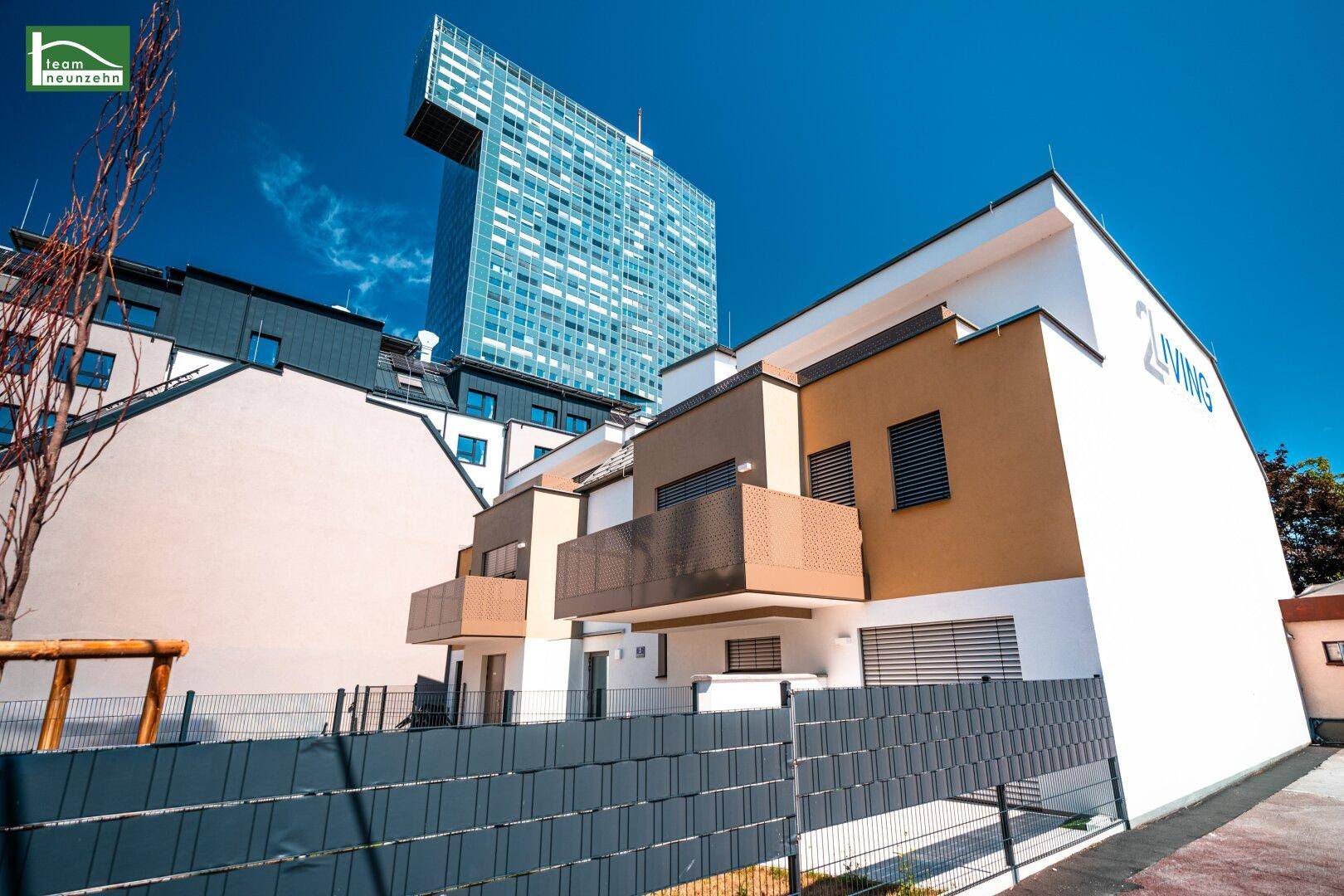 Neubau-Reihenhäuser mit moderner Architektur und einem hohen Gebäude im Hintergrund.