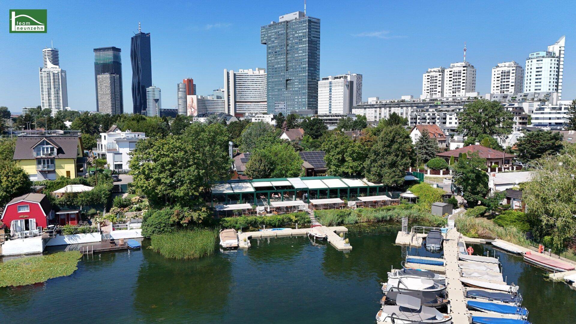 Luftaufnahme der Stadt mit See, Häusern am Ufer und modernen Hochhäusern im Hintergrund.