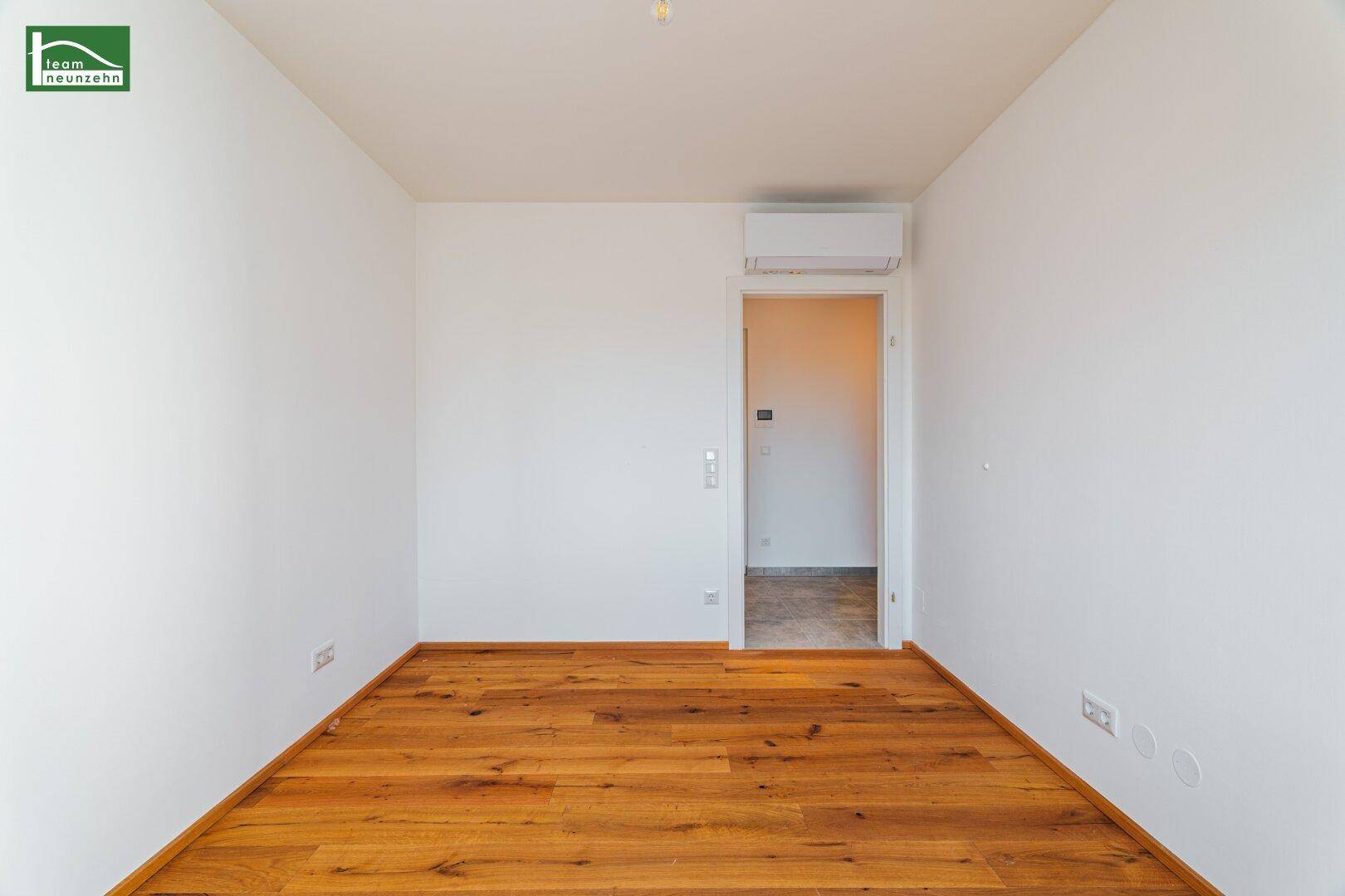 Unmöbliertes Zimmer mit Holzboden und Klimaanlage, bereit für individuelle Gestaltung.