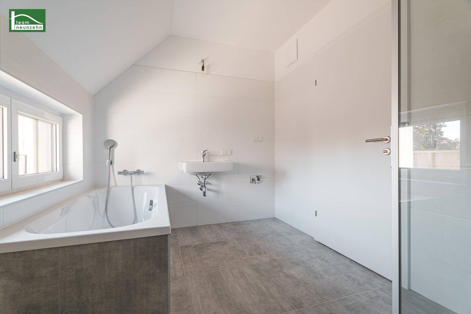 Geräumiges Badezimmer mit Badewanne, Waschbecken und Duschbereich, hell und modern.