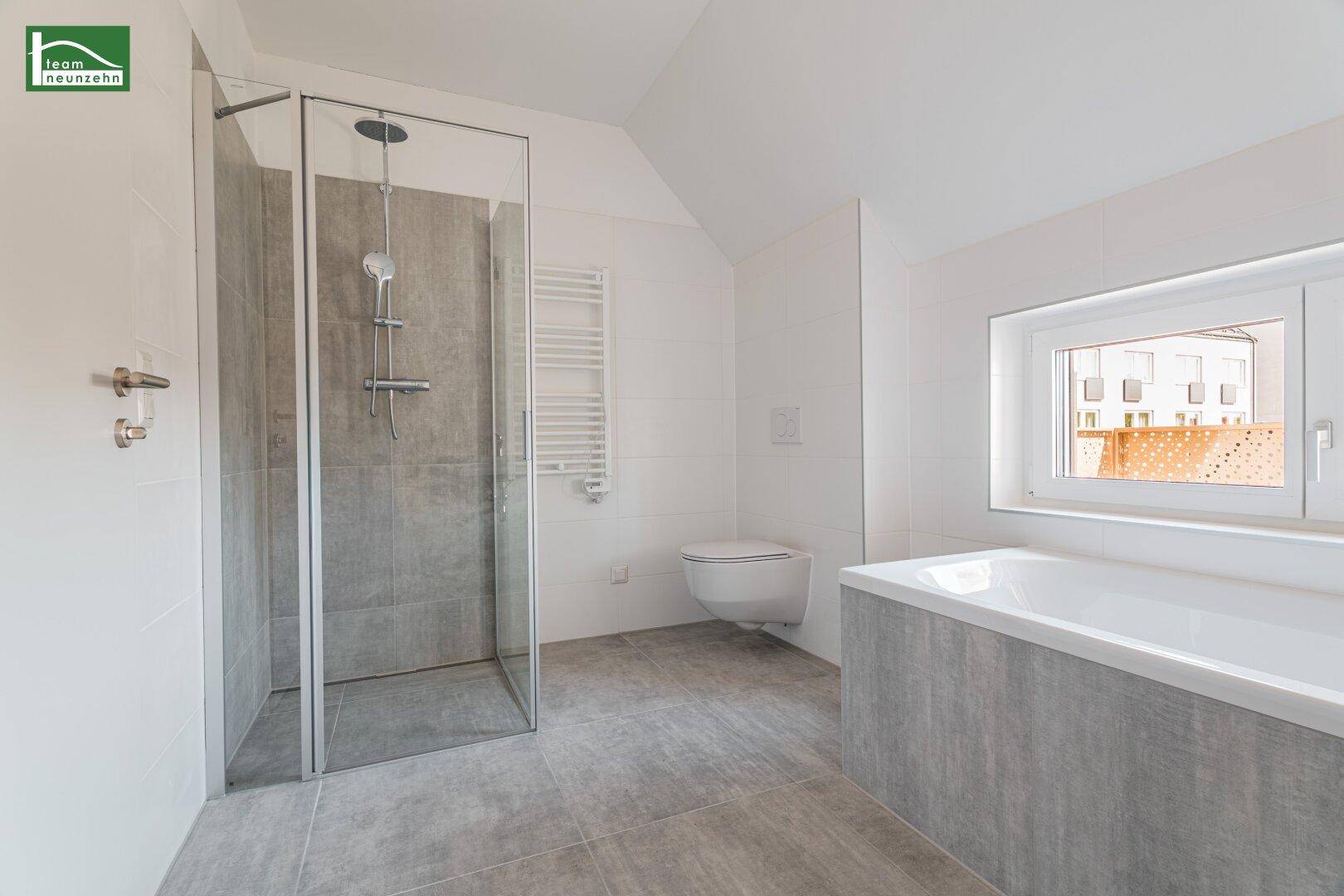 Modernes Badezimmer mit Badewanne, ebenerdiger Dusche und beheiztem Handtuchhalter.