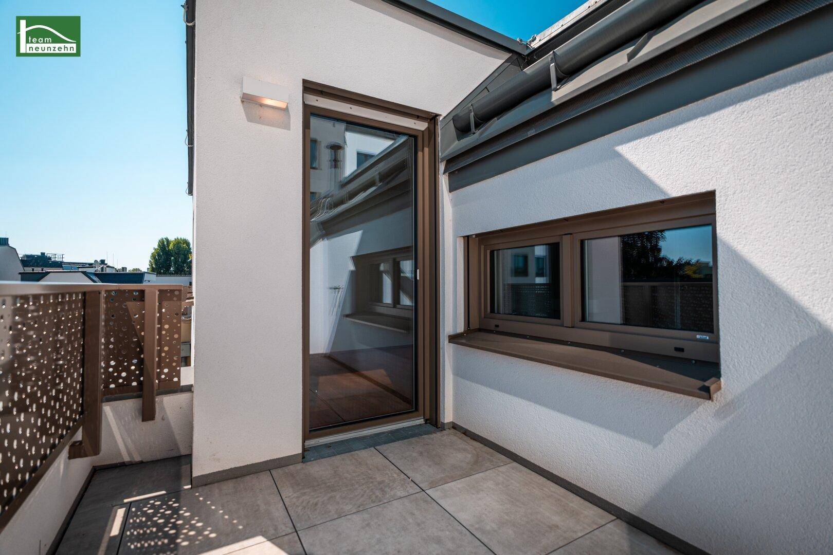 Terrassenzugang mit Fenster und Blick auf die umliegenden Gebäude und Bäume.