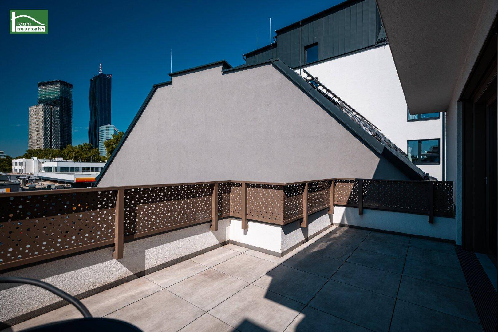 Große Dachterrasse mit Stadtblick und moderner Architektur im Hintergrund.