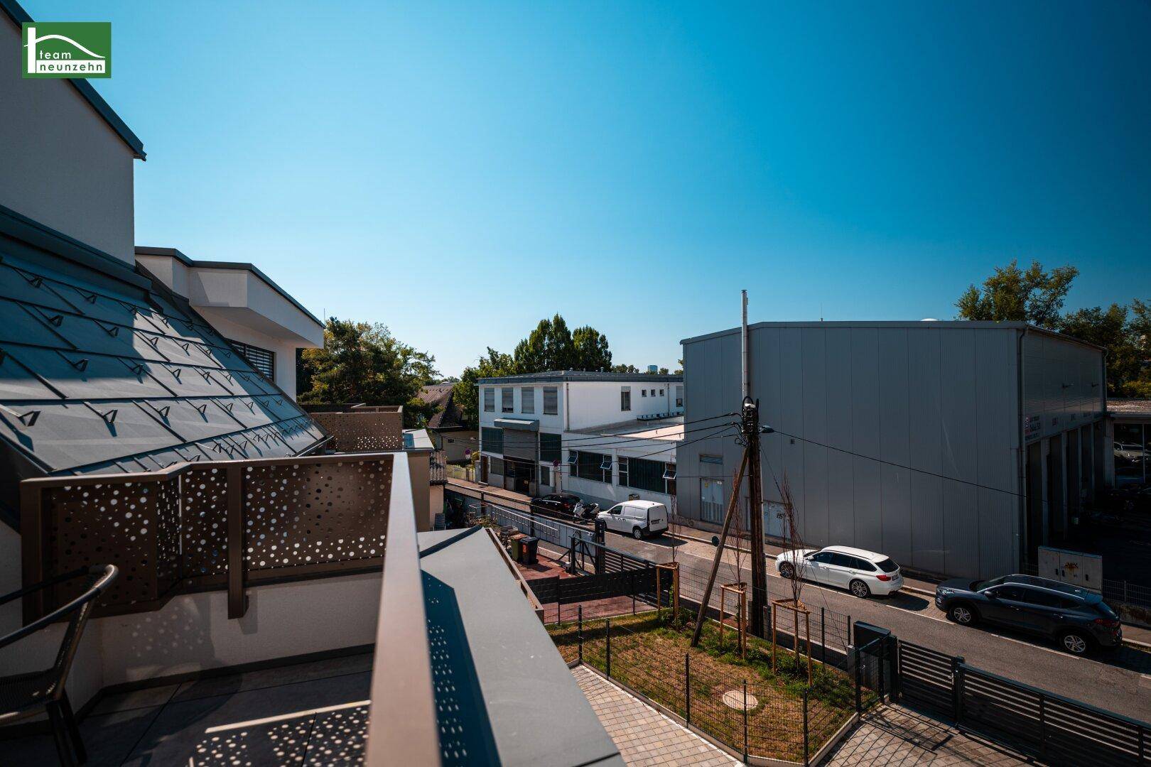 Terrasse mit Blick auf die Straße und die umliegenden Gebäude, sonnig und offen.