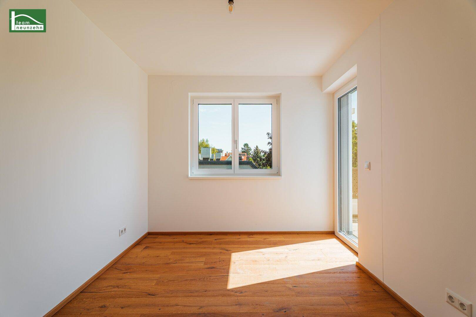 Sonniger Raum mit Holzboden und Fenster, das viel Tageslicht hereinlässt.