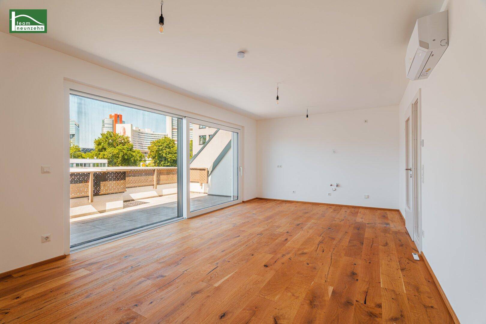 Geräumiges Wohnzimmer mit Holzboden und Schiebetüren, die viel Tageslicht hereinlassen.