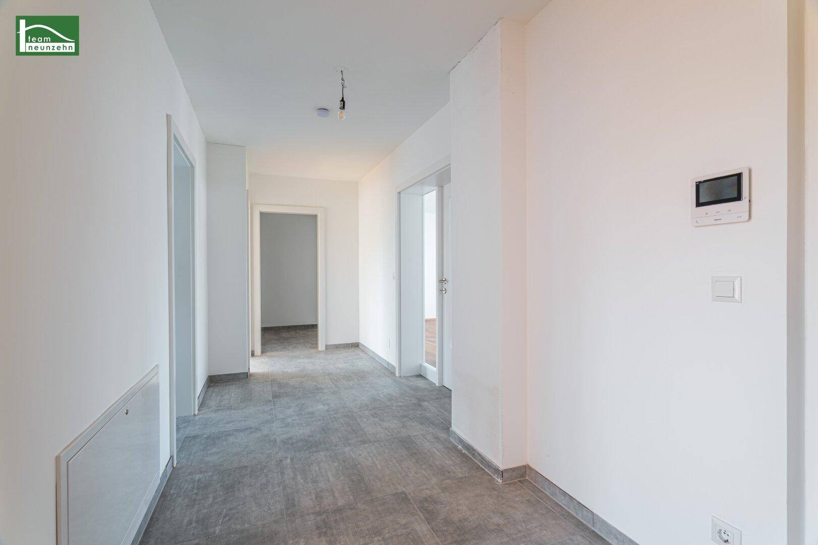 Heller Flur mit Fliesenboden und Zugang zu verschiedenen Räumen der Wohnung.