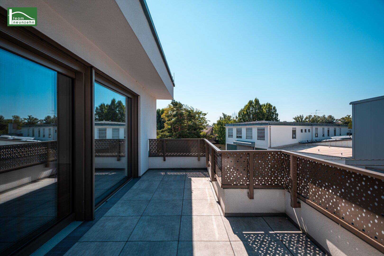 Große, sonnige Terrasse mit Fliesenboden und Blick auf die Umgebung.