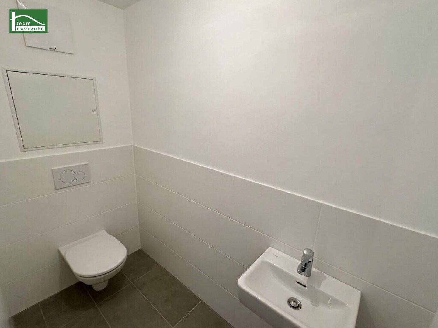 Separates Gäste-WC mit Wand-WC und kleinem Waschbecken, in modernem Design.