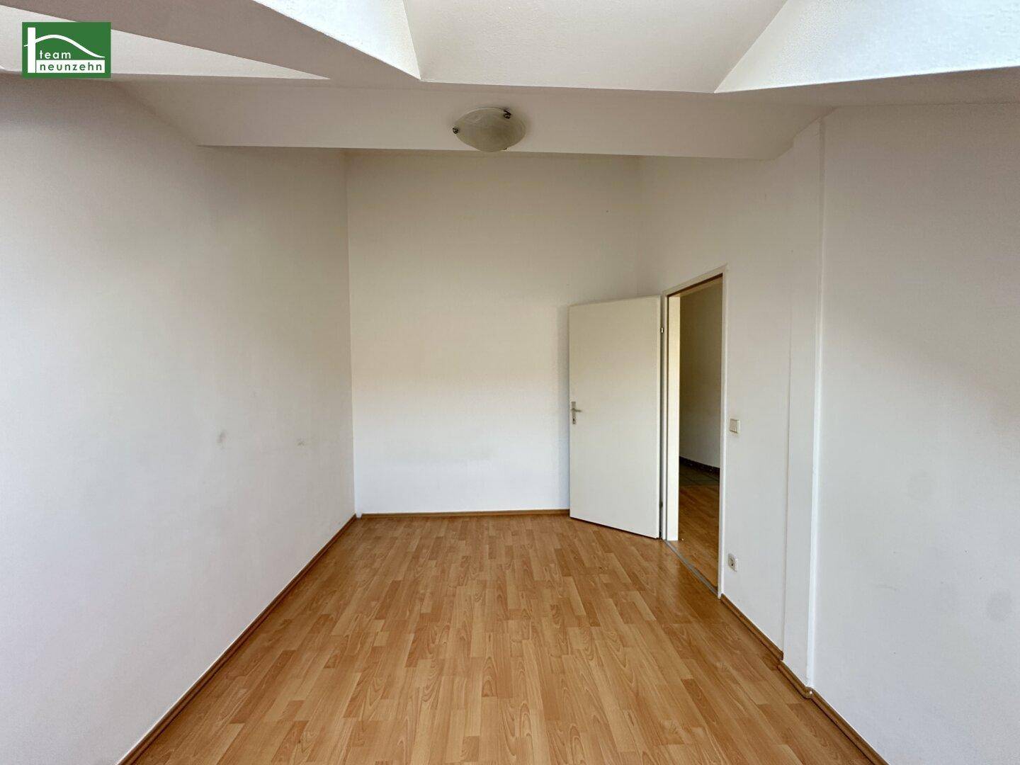 Leeres Zimmer mit Holzboden und weiß gestrichenen Wänden, bereit zur Einrichtung.