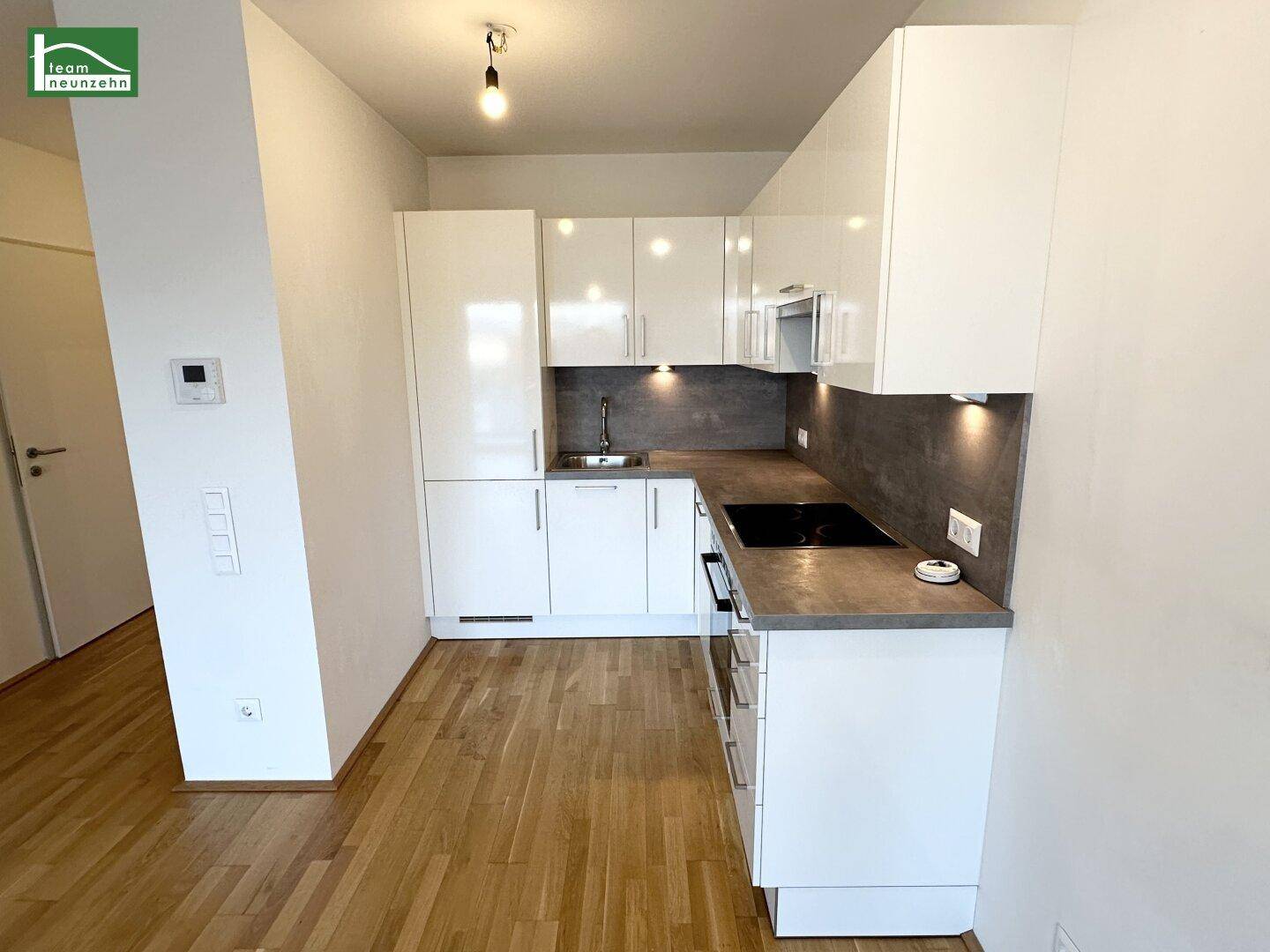 Moderne Einbauküche mit weißen Hochglanzfronten und Induktionskochfeld.
