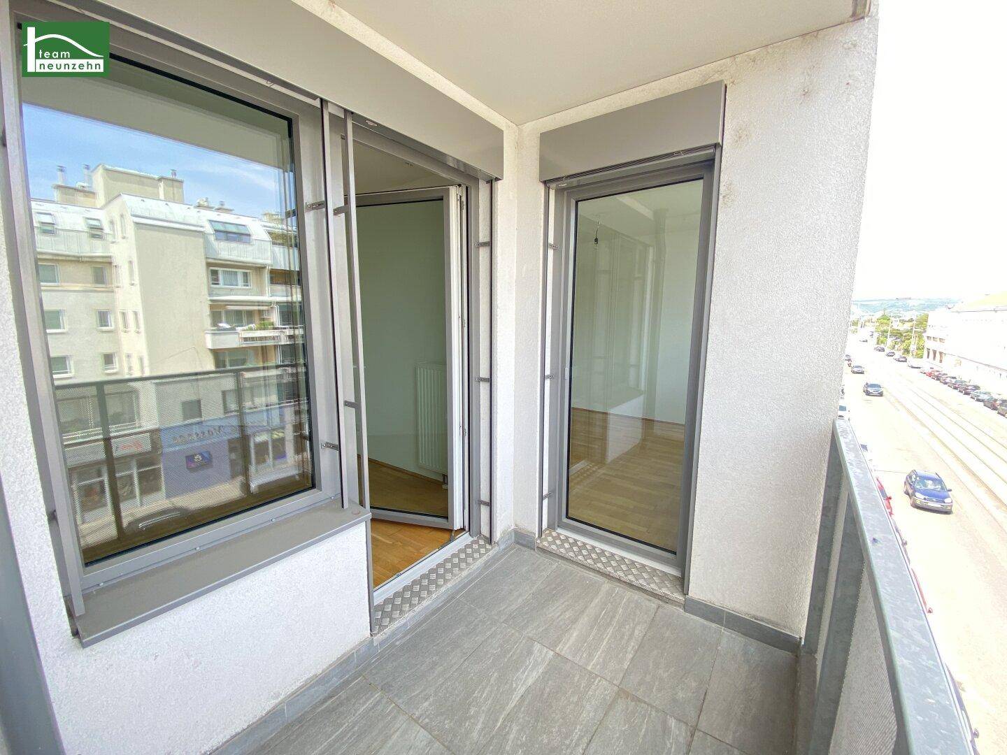Balkon mit Fliesenboden und Blick auf die Stadt und umliegende Gebäude.