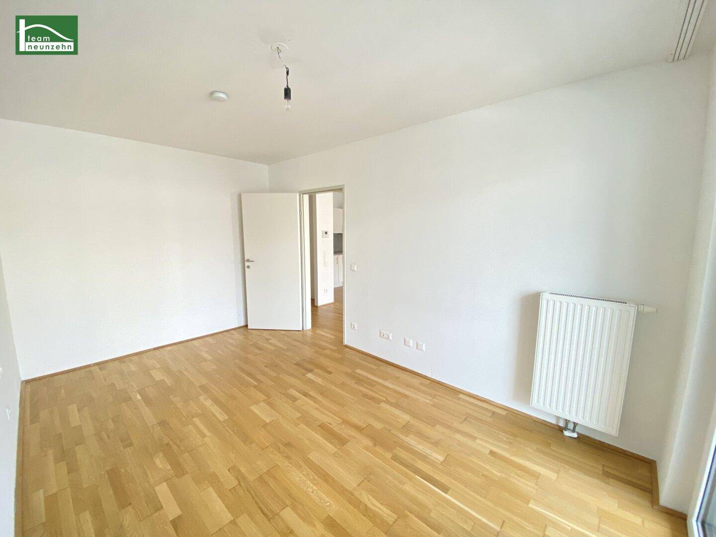 Geräumiges Zimmer mit Holzboden und viel Tageslicht, ideal als Schlafzimmer.