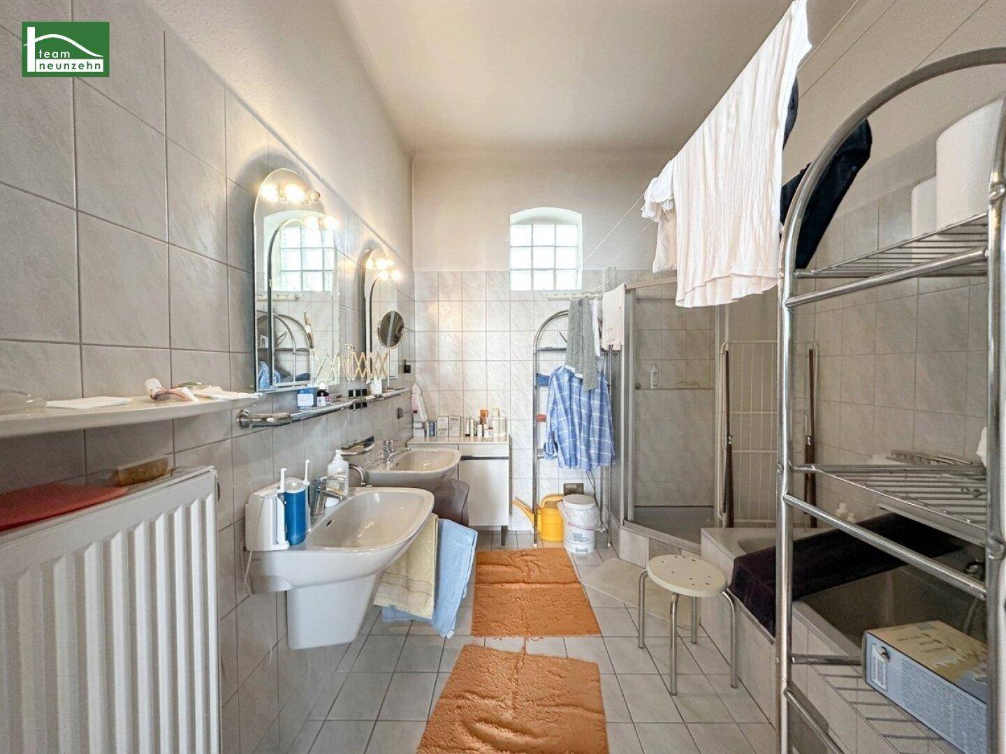 Geräumiges Badezimmer mit Doppelwaschbecken, Dusche und Badewanne, hell gefliest.