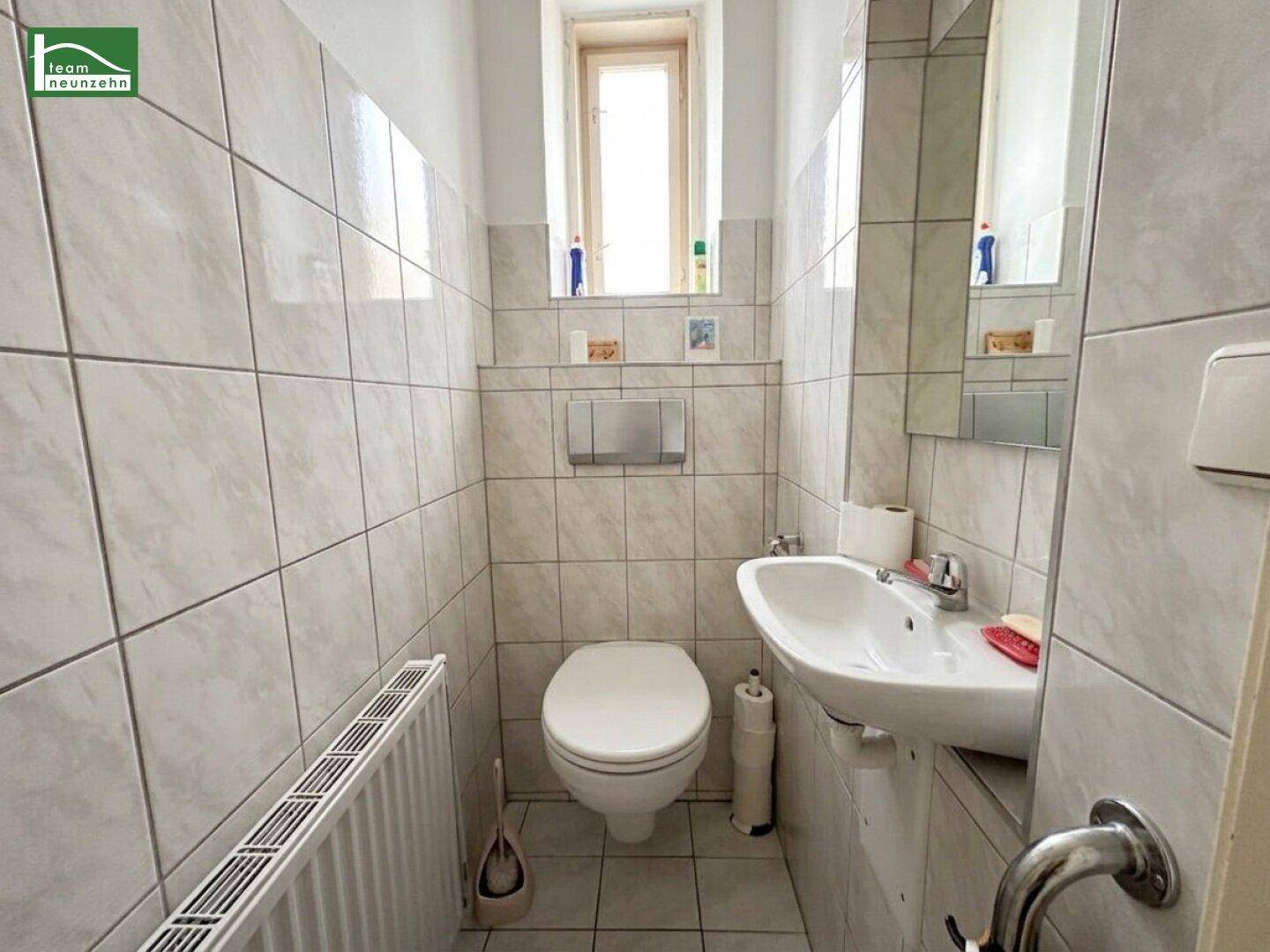 Kleines Gäste-WC mit Fenster, Wand-WC und Waschbecken, komplett gefliest.