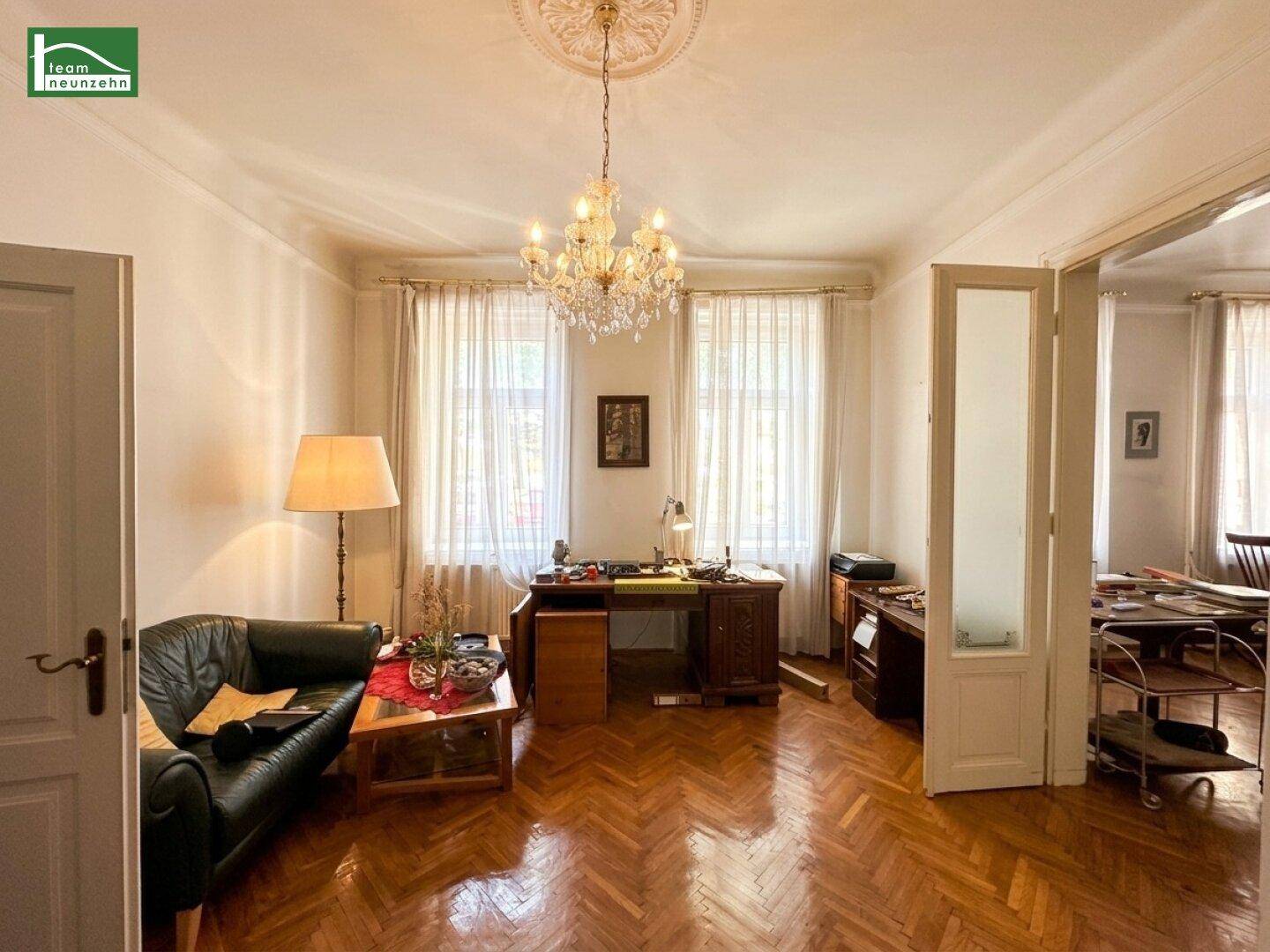 Großes Zimmer mit Fischgrätparkett, hohen Decken und viel Tageslicht, vielseitig nutzbar.