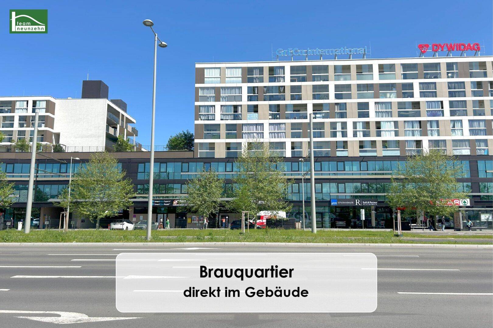 Weitläufige Ansicht der modernen Architektur mit Geschäften und viel Grün in der Umgebung.