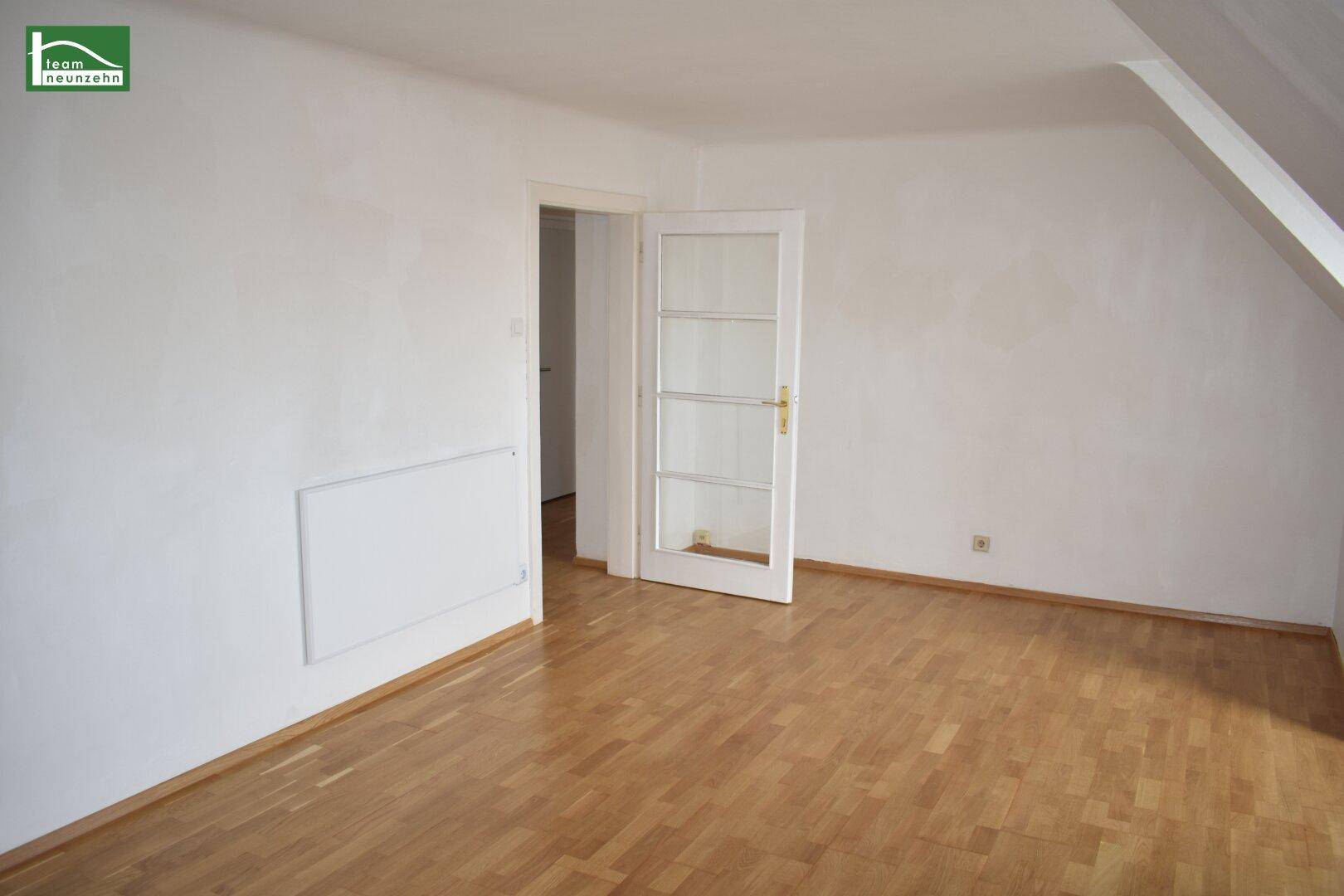 Geräumiges Zimmer im Dachgeschoss mit Parkettboden und einer Tür zu weiteren Räumen.