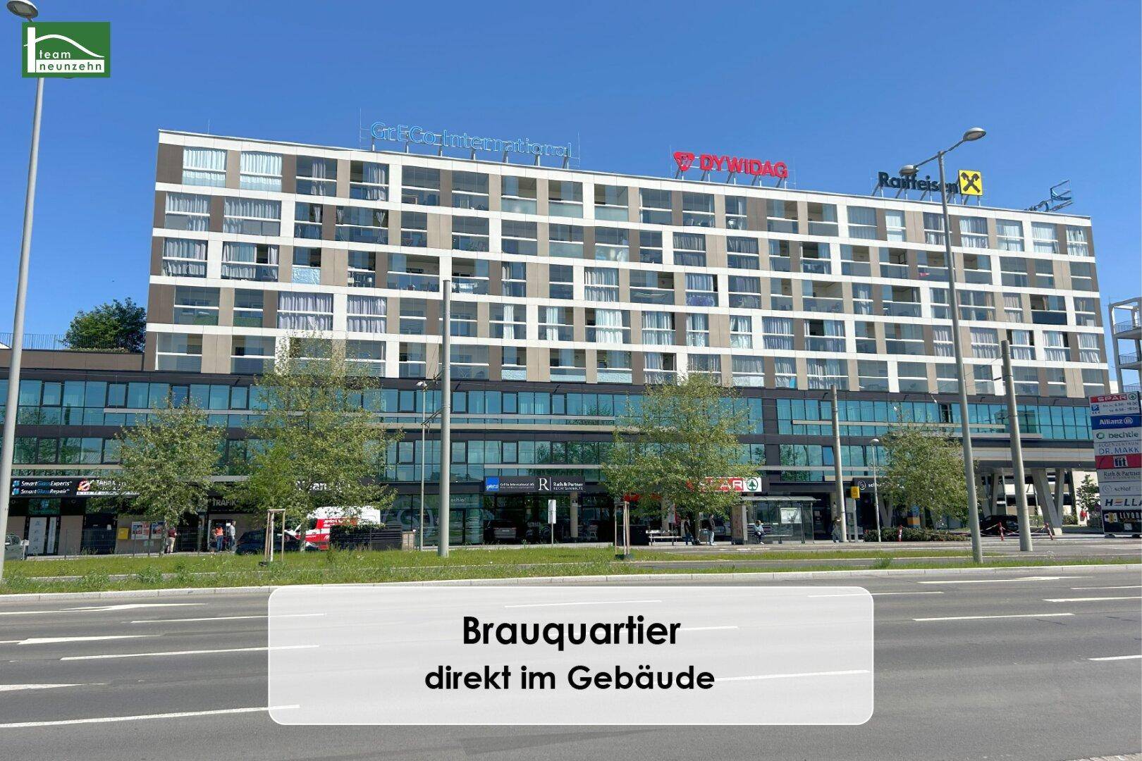 Moderne Fassade eines Wohn- und Geschäftsgebäudes im Brauquartier unter blauem Himmel.
