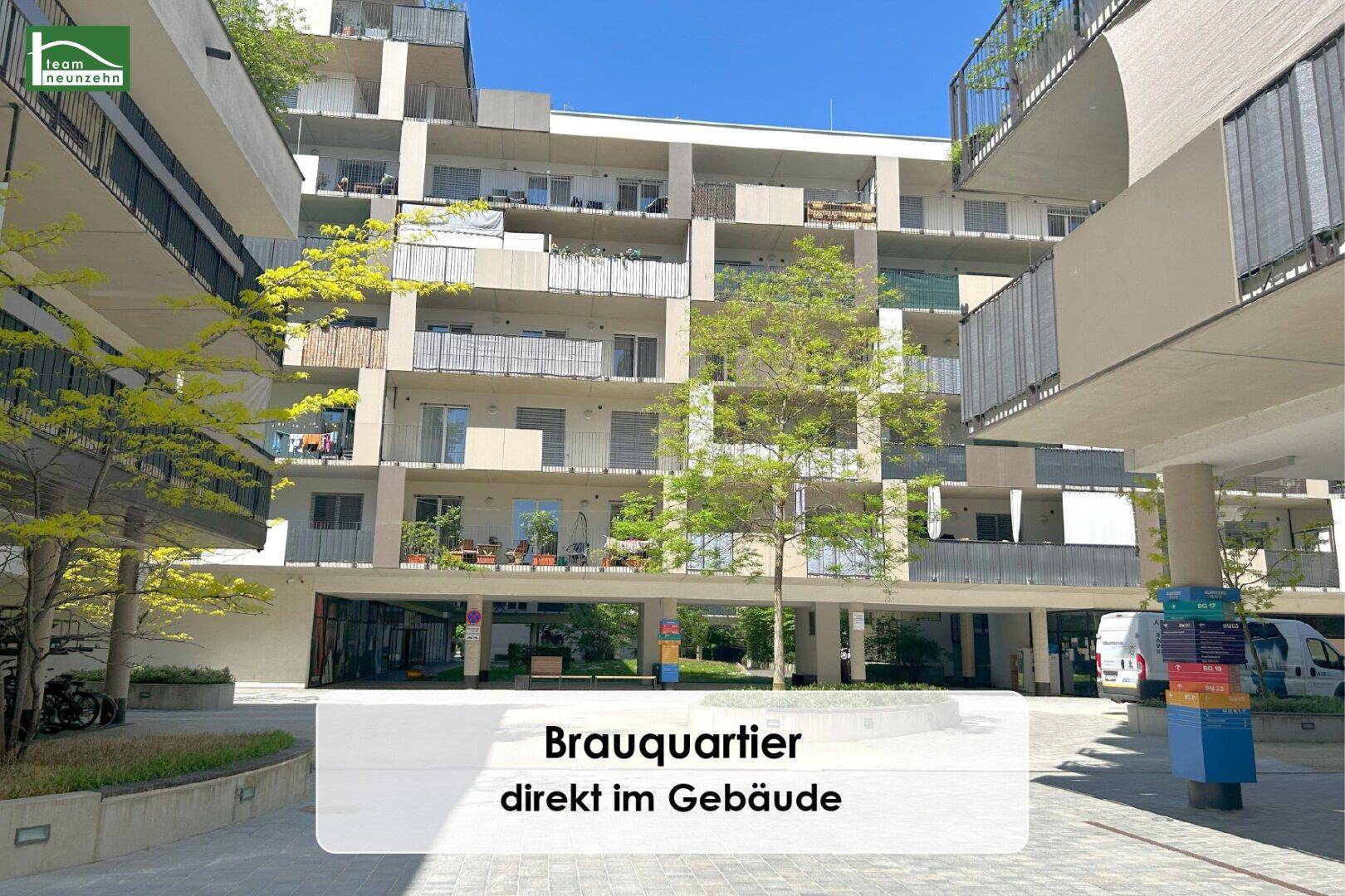Innenhofansicht eines modernen Wohnkomplexes mit Grünflächen und Balkonen.