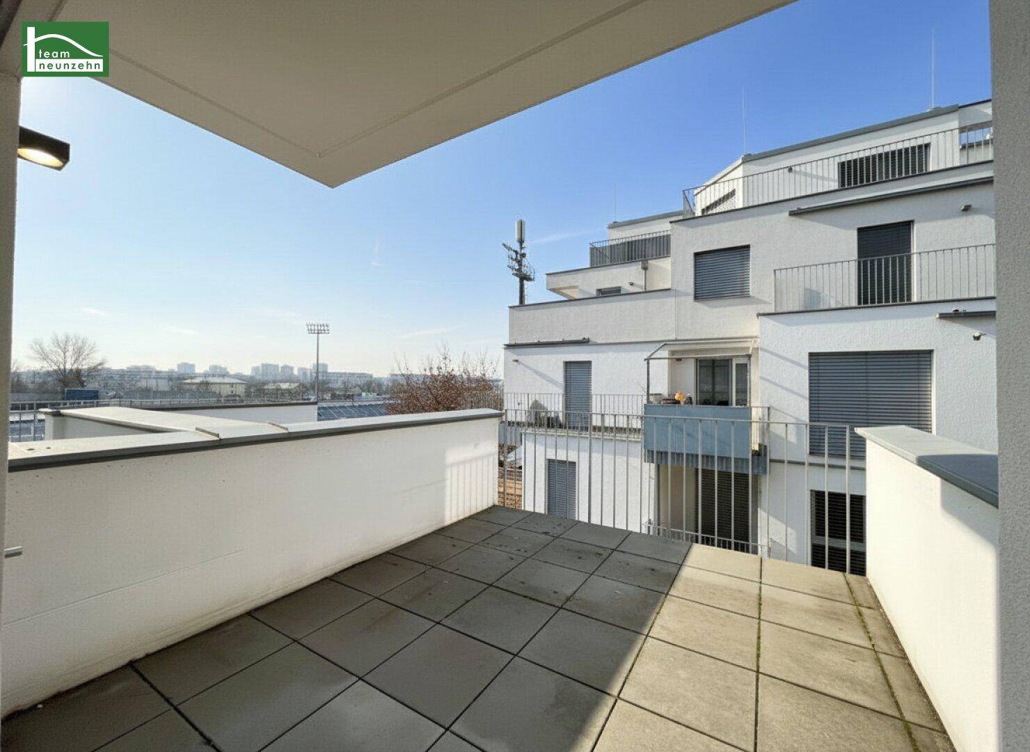 Geräumiger Balkon mit Fliesenboden und Blick auf die umliegenden Wohngebäude.