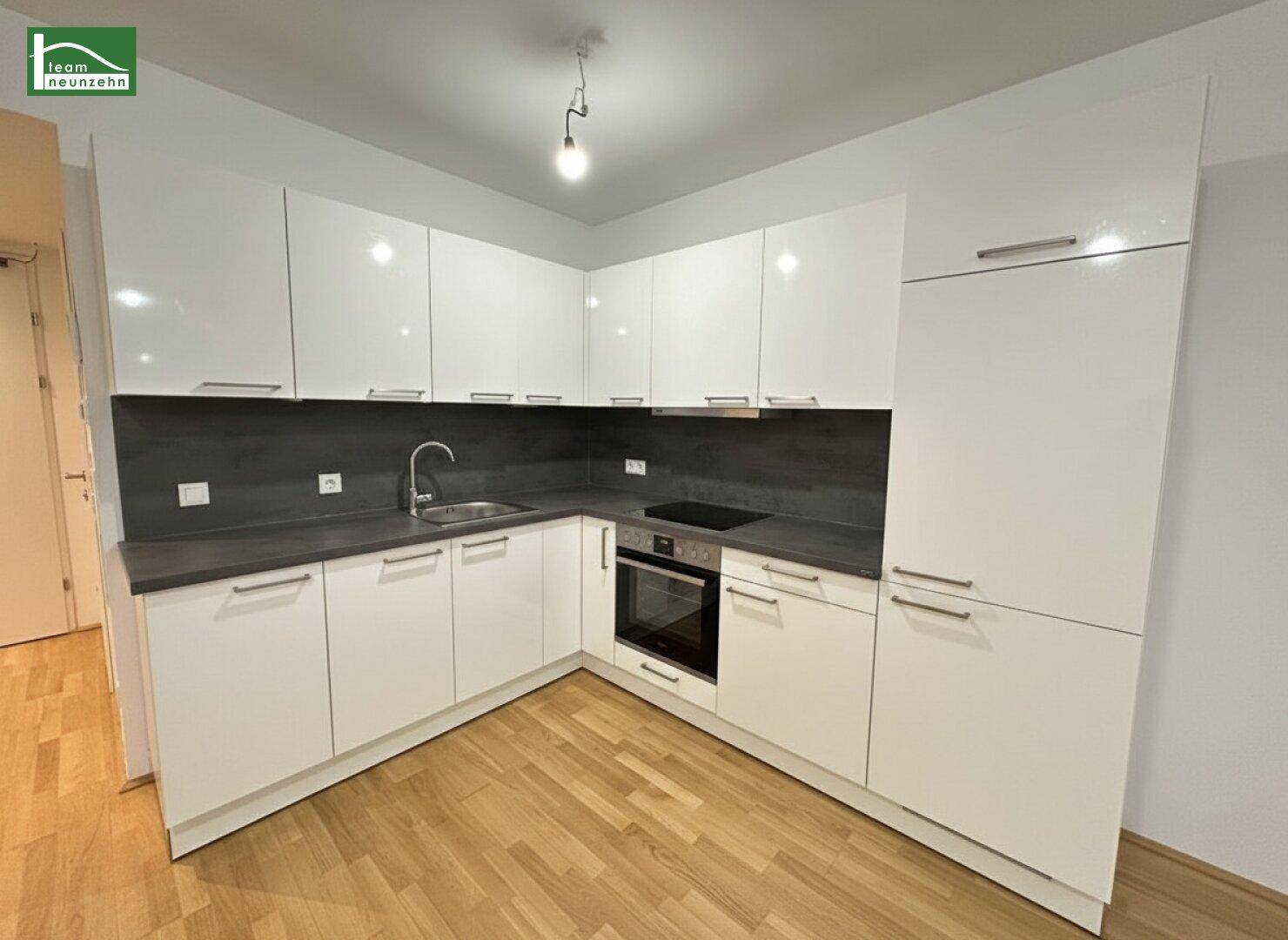 Moderne Einbauküche mit weißen Hochglanzfronten, integriertem Backofen und Induktionskochfeld.