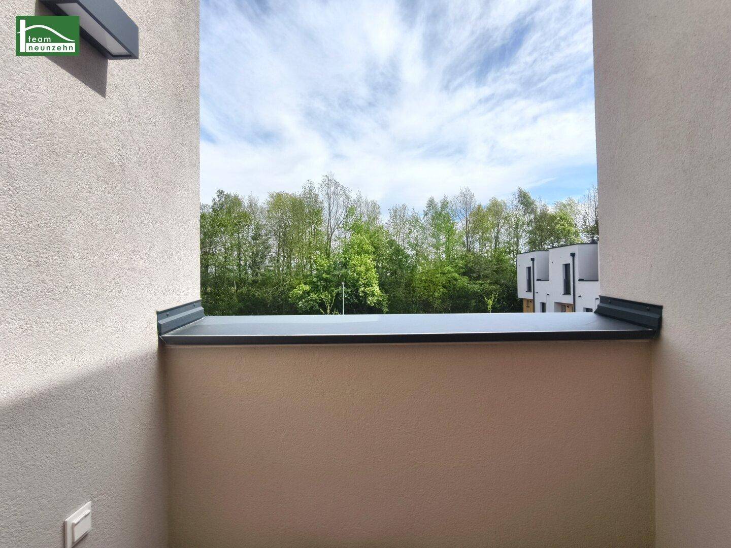 Französischer Balkon mit Geländer und weitem Blick auf grüne Bäume und Natur.