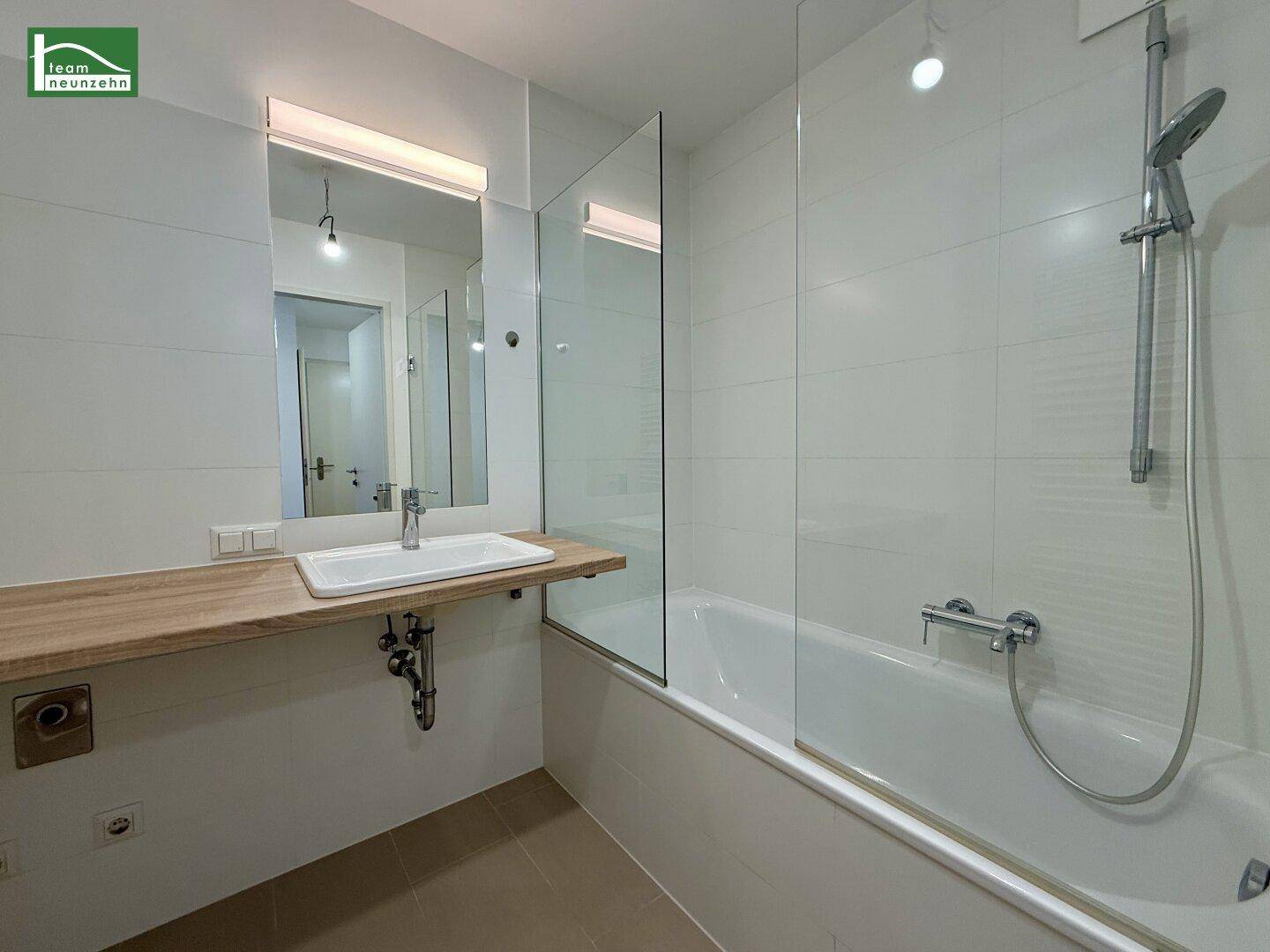 Modernes Badezimmer mit Badewanne, Duschabtrennung aus Glas und Einzelwaschbecken.