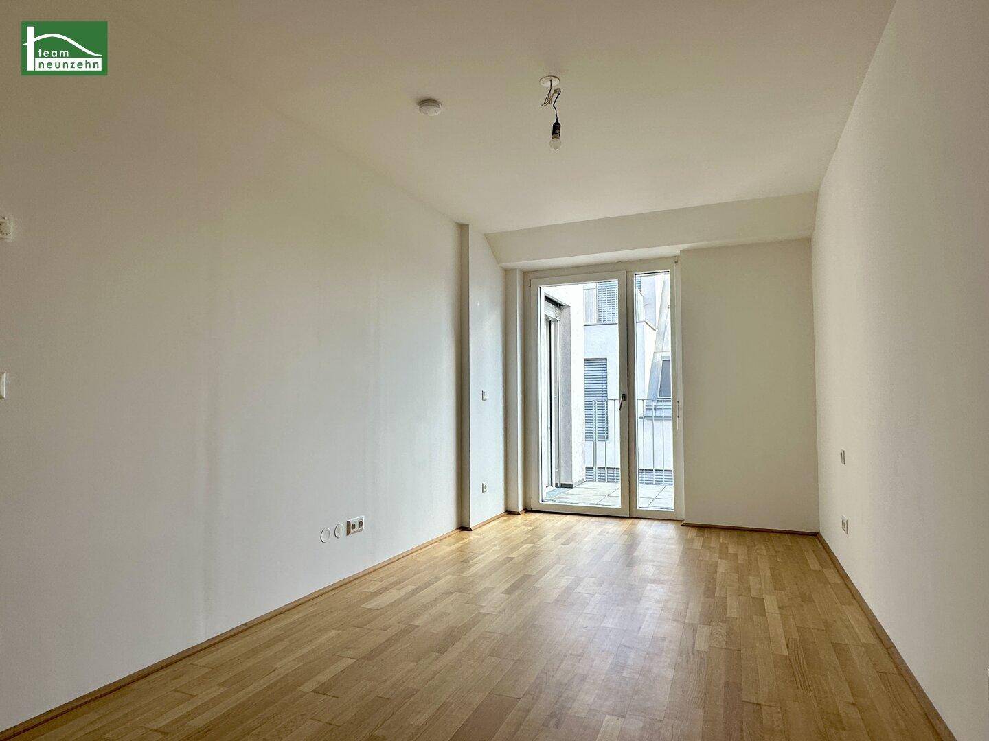 Leeres Zimmer mit Parkettboden und Balkonzugang, ideal als Schlaf- oder Arbeitszimmer.