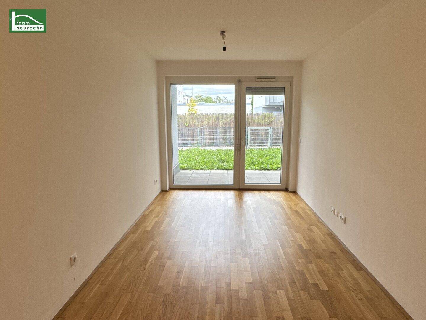 Heller Wohnraum mit Parkettboden und großen Schiebetüren, die zu einem Gartenbereich führen.