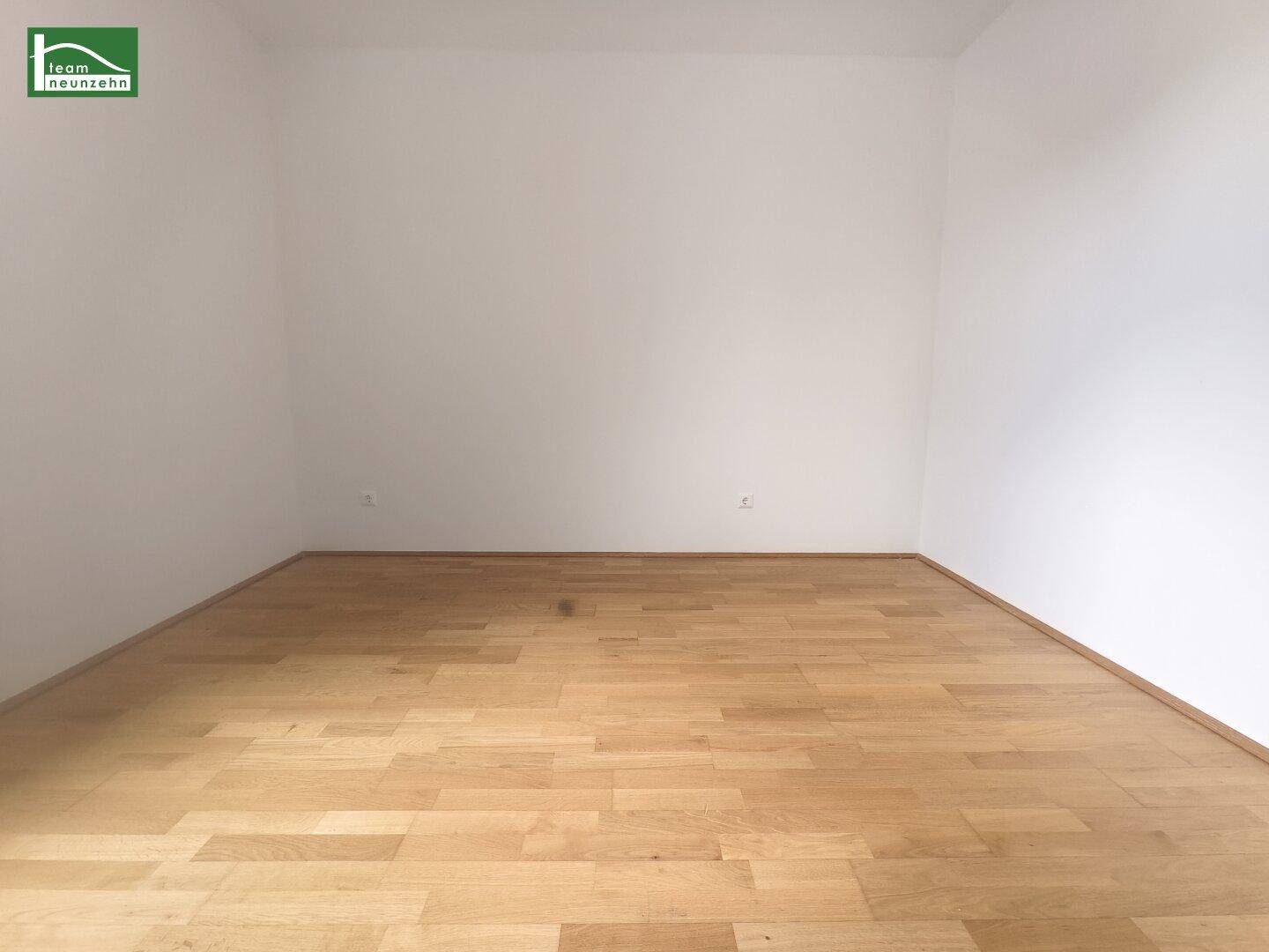 Leerer Raum mit hellen Wänden und warmem Parkettboden, bereit zur individuellen Gestaltung.