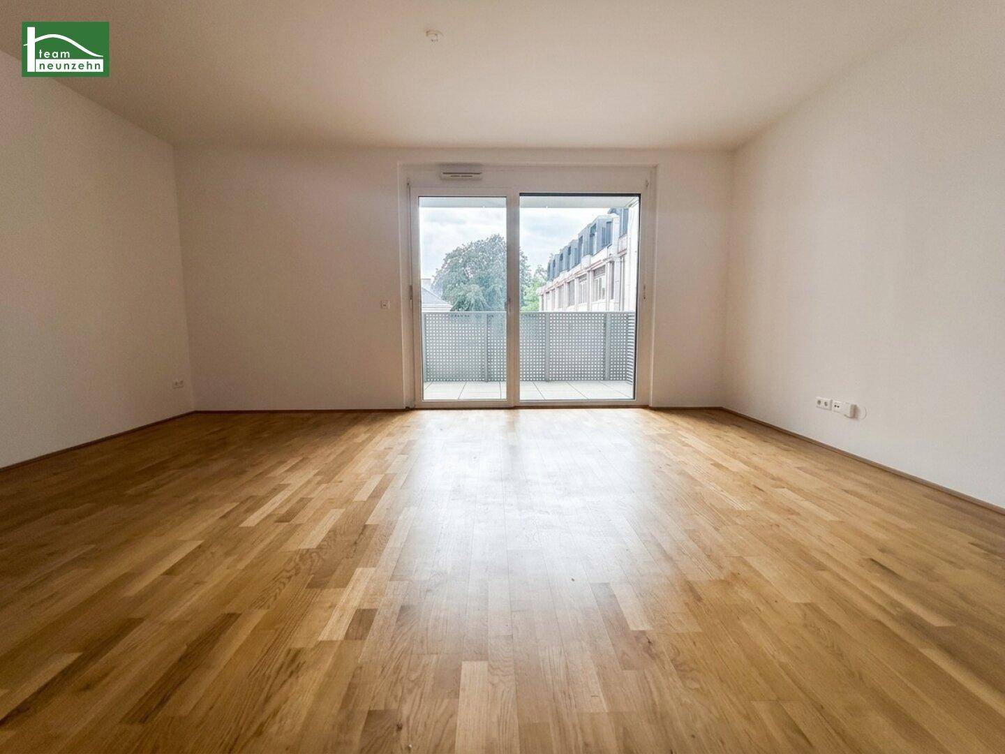 Geräumiger, heller Wohnraum mit Parkettboden und Zugang zu einem Außenbereich.