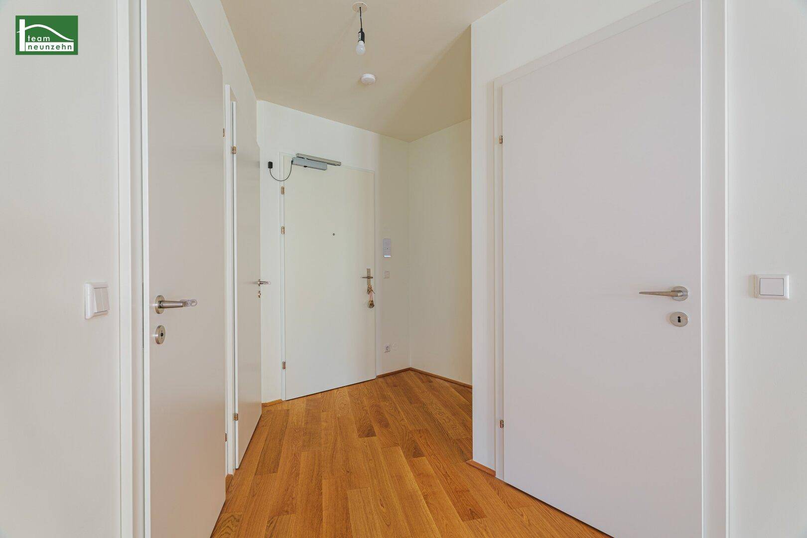 Heller Eingangsbereich mit Holzparkett und mehreren Türen zu den angrenzenden Räumen der Wohnung.
