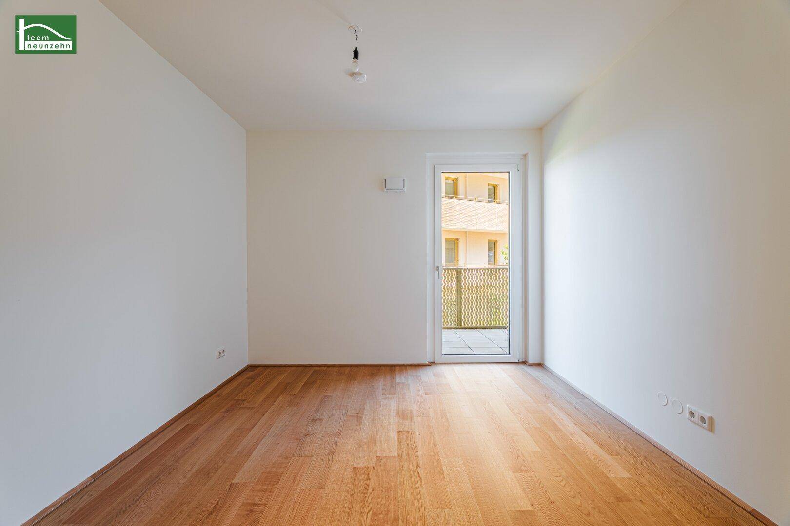 Ruhiges Schlafzimmer mit Parkettboden und Zugang zu einem kleinen Balkon, ideal für Erholung.