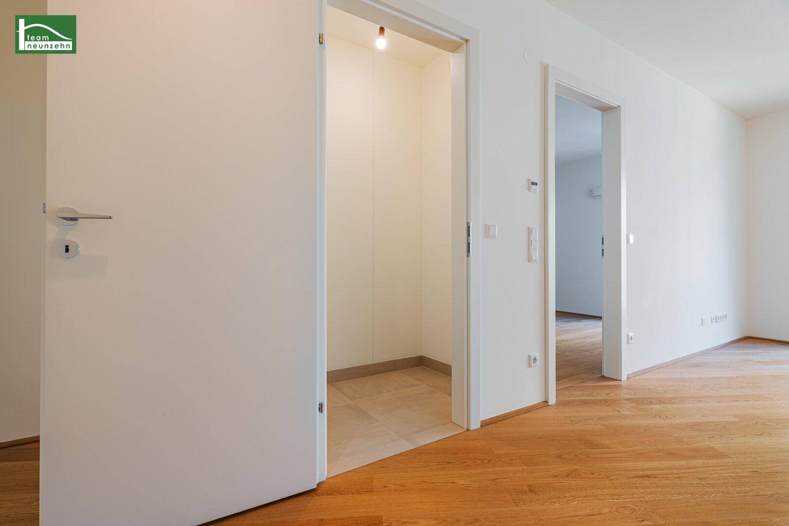 Heller Flur mit Holzparkettboden und Zugang zu einem praktischen Abstellraum mit Fliesen.
