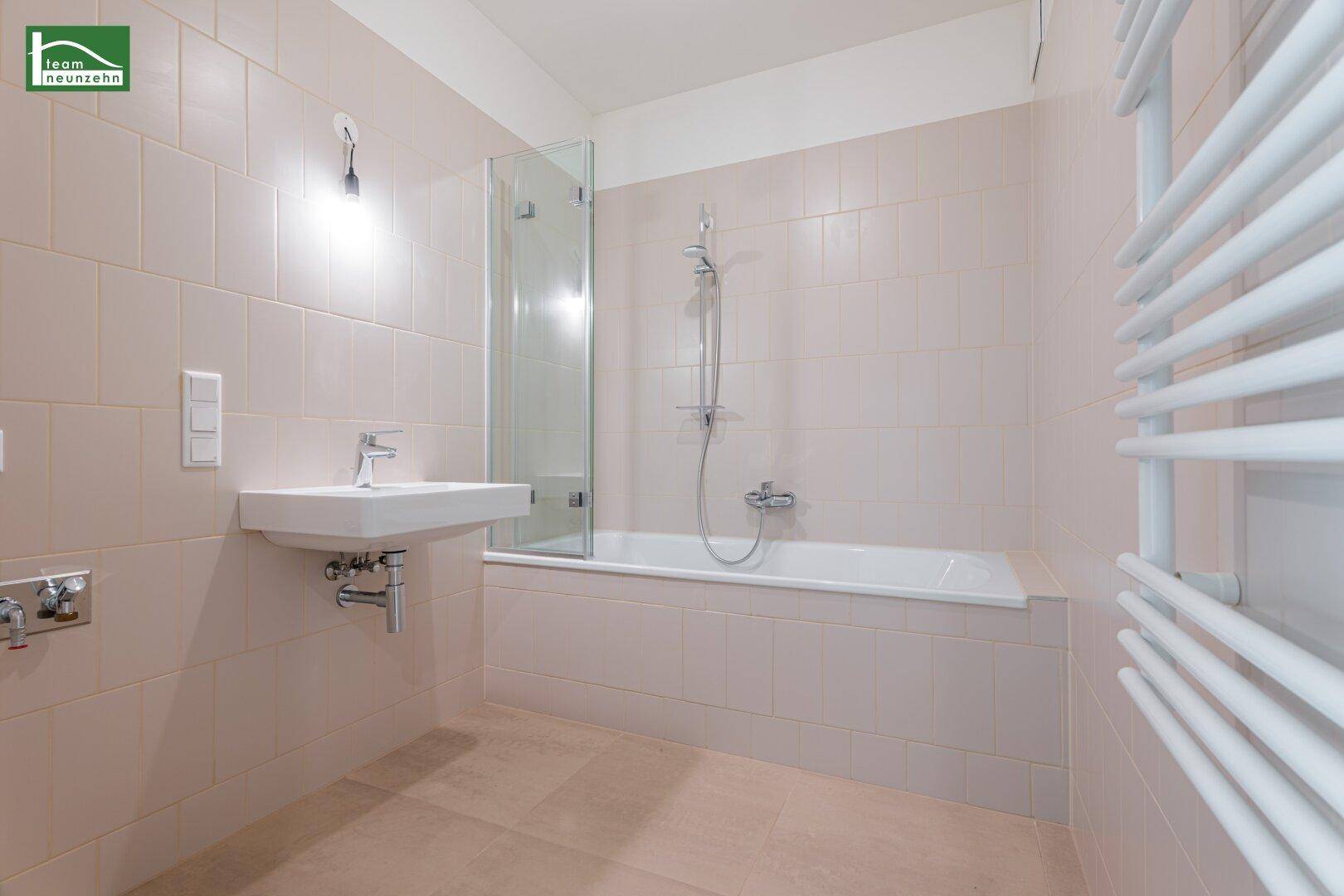 Modernes Badezimmer mit Badewanne, Dusche und beheiztem Handtuchhalter.