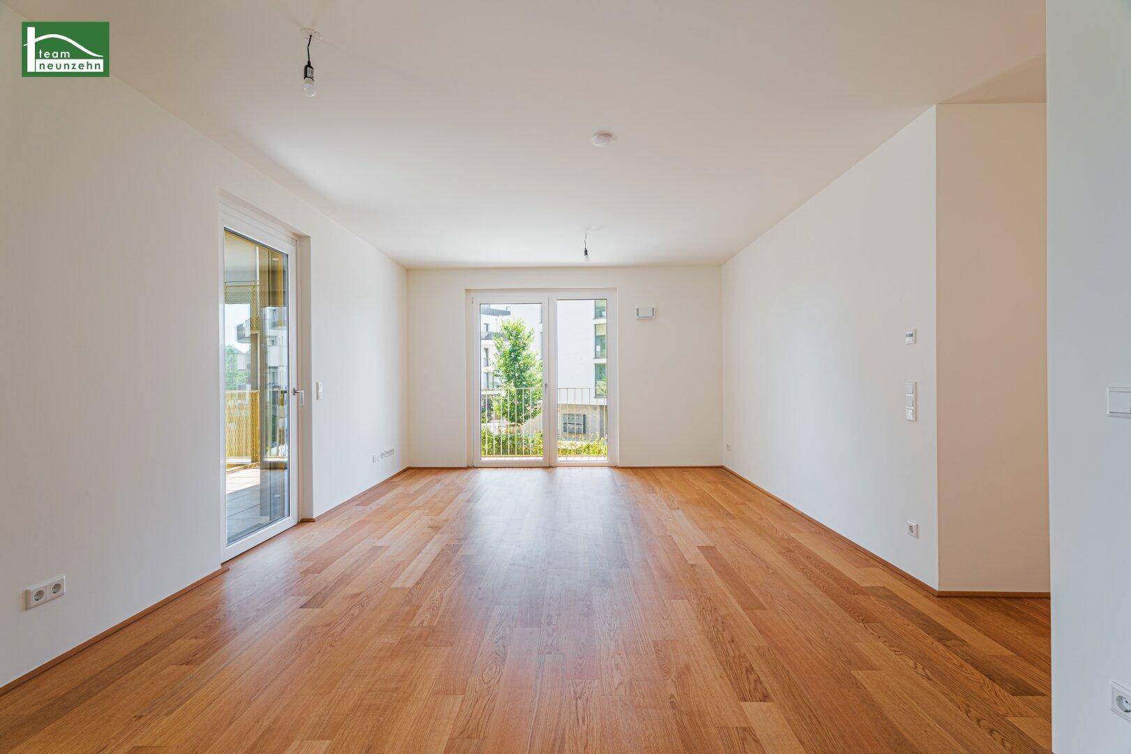 Geräumiger, leerer Raum mit Holzboden und zwei Balkonzugängen, ideal für Wohn- oder Schlafzimmer.