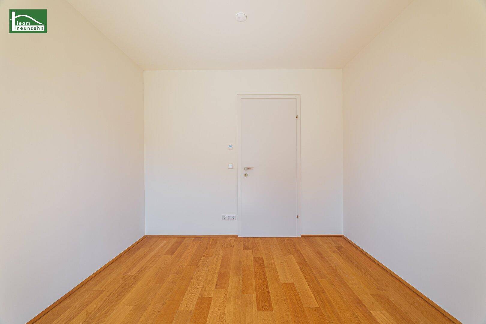 Unmöbliertes Schlafzimmer mit Holzboden und schlichten weißen Wänden, ideal für persönliche Einrichtung.