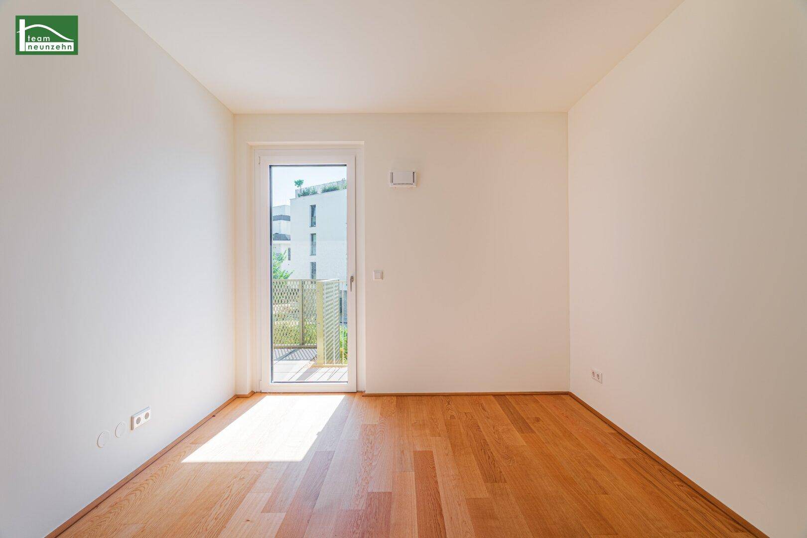 Helles Schlafzimmer mit Holzboden, weißen Wänden und direktem Zugang zu einem kleinen Balkon.